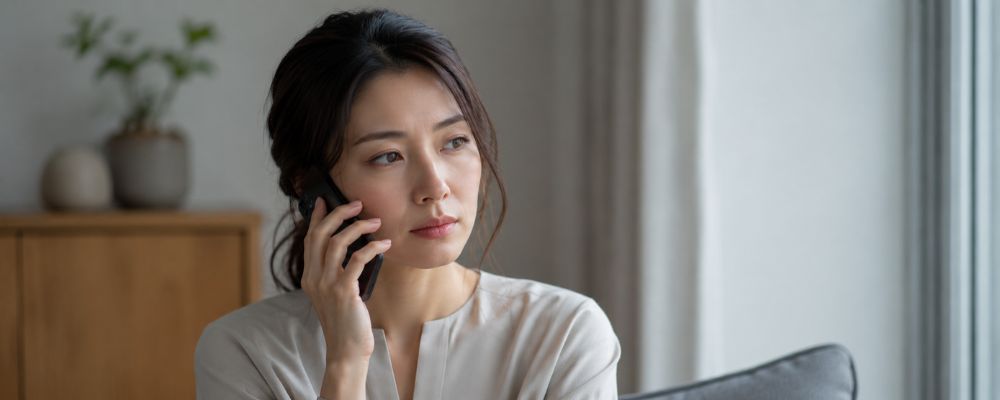 電話占いのからくりに警戒しながらスマホで相談する女性